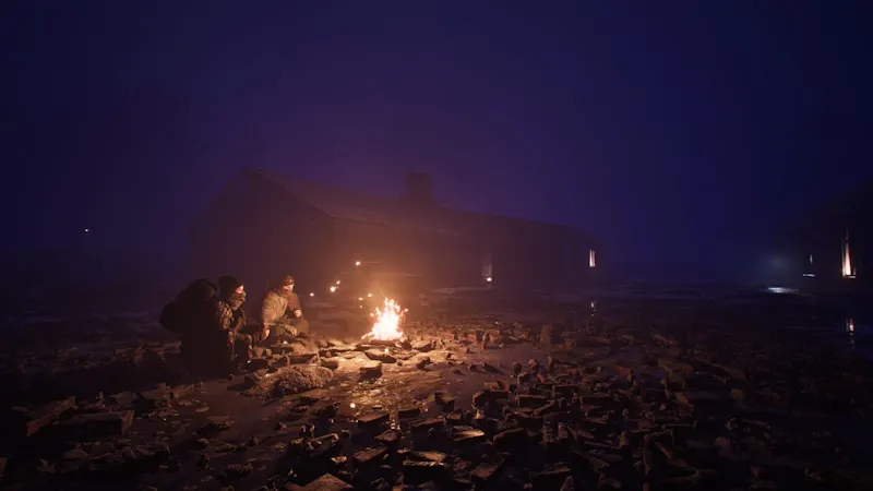 Characters sitting around the fire in the night.